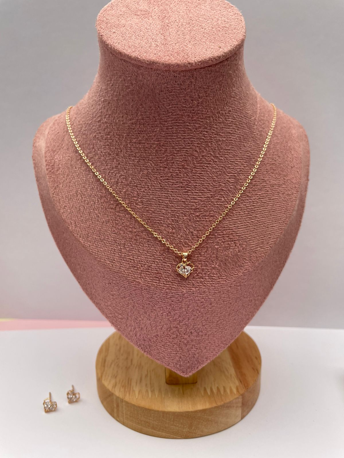 Set de joyas de collar y aretes con diseño de flor dorada y perla central, presentado en una elegante caja de joyería color beige.