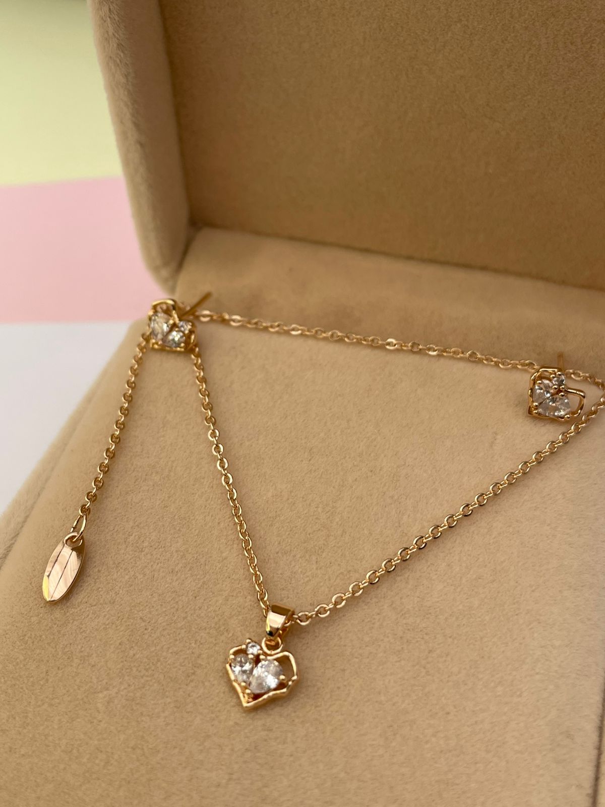 Set de joyas de collar y aretes de corazón con cristales, presentado de forma elegante en una caja de joyería color beige
